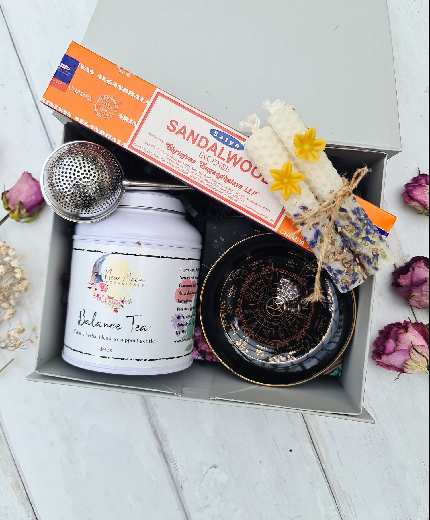 Gift set with tea, sandalwood incense, and other items in a box on a wooden surface.