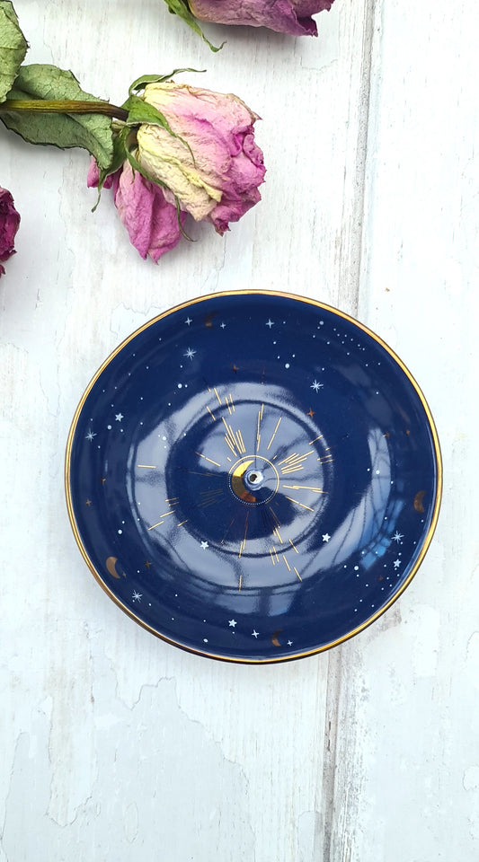 Blue ceramic plate with gold rim on a white wooden surface with dried pink roses.