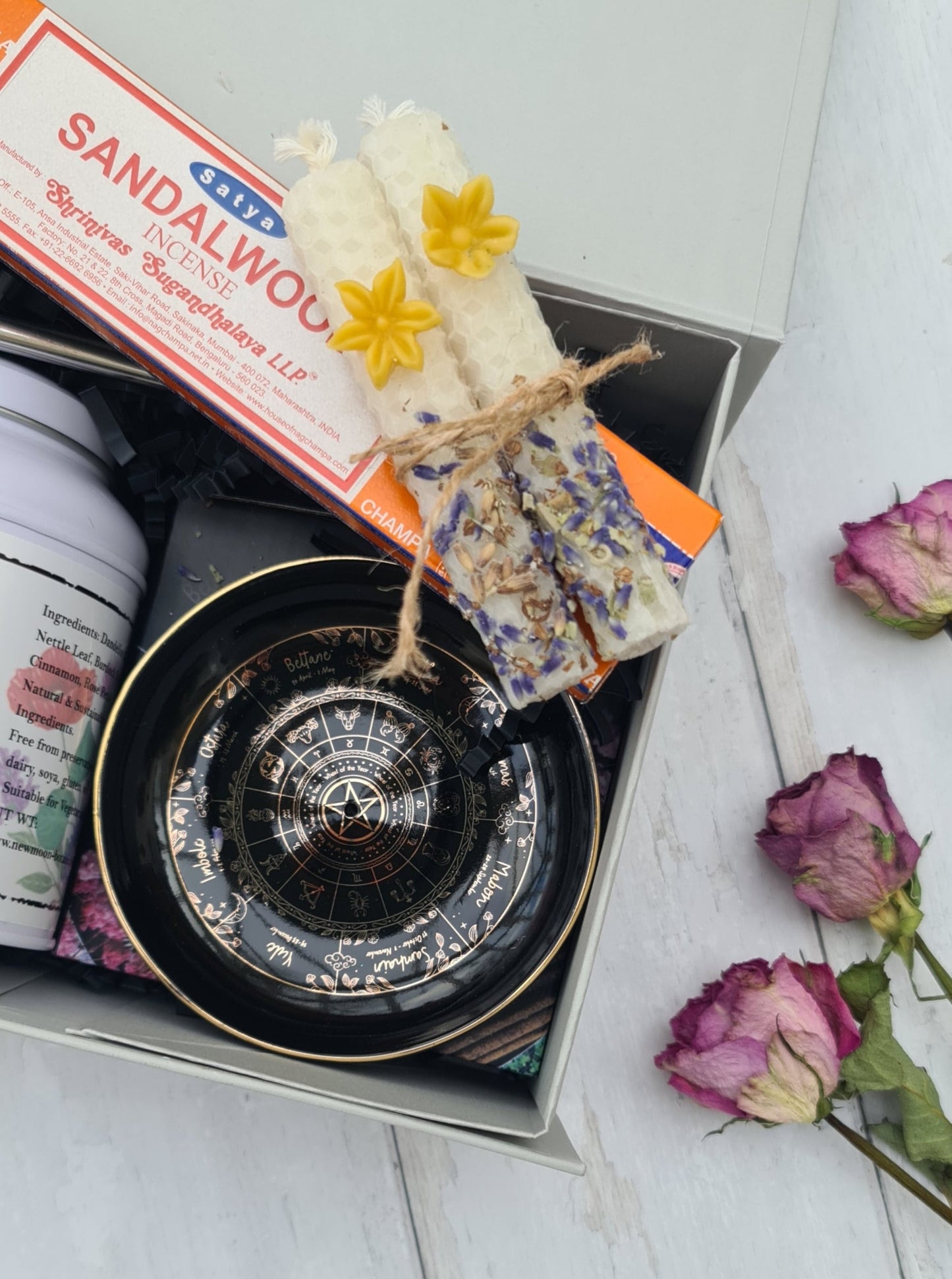 Sandalwood incense stick with decorative packaging and flowers on a white surface