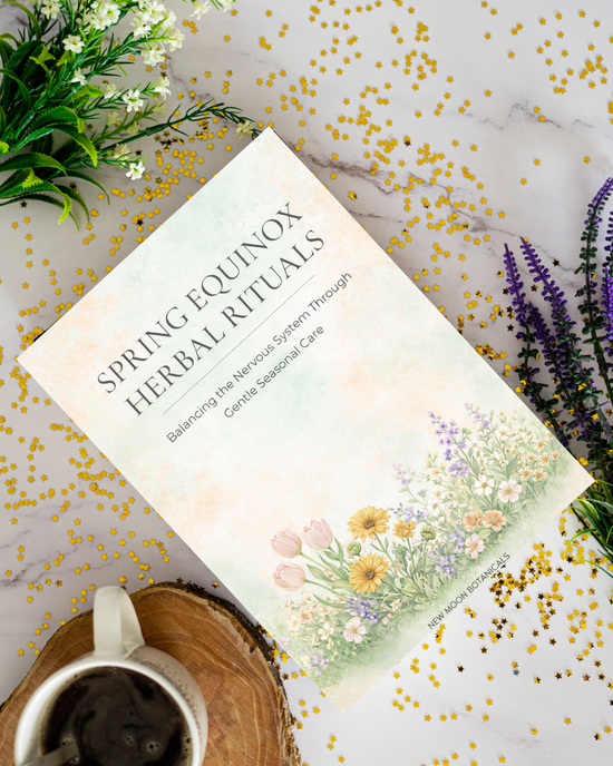 Book titled 'Spring Equinox Herbal Rituals' on a decorative surface with flowers and a mug.